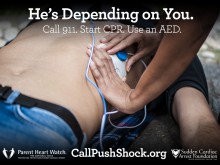 Woman places defibrillator pad on man